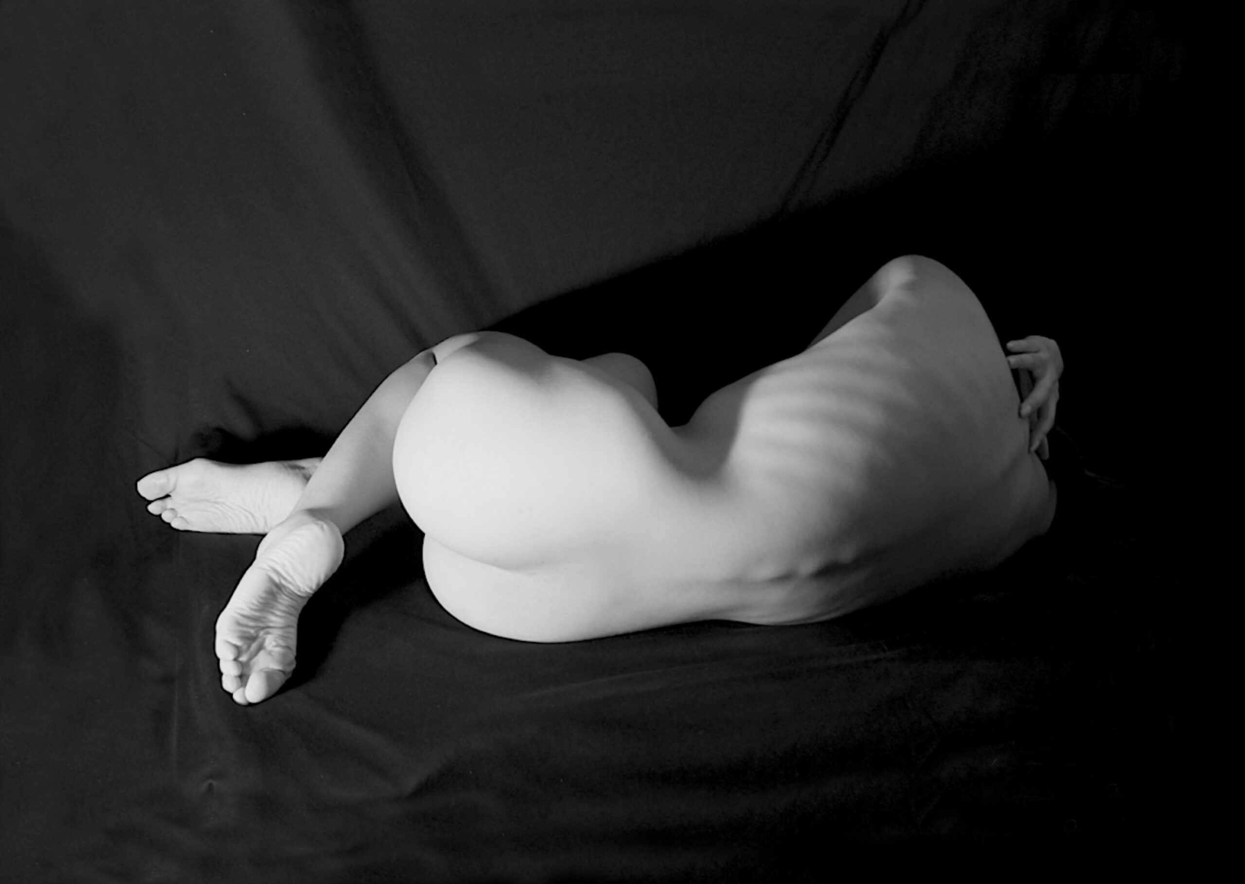 a woman's figure as a bodyscape, viewed from the back, reclining.